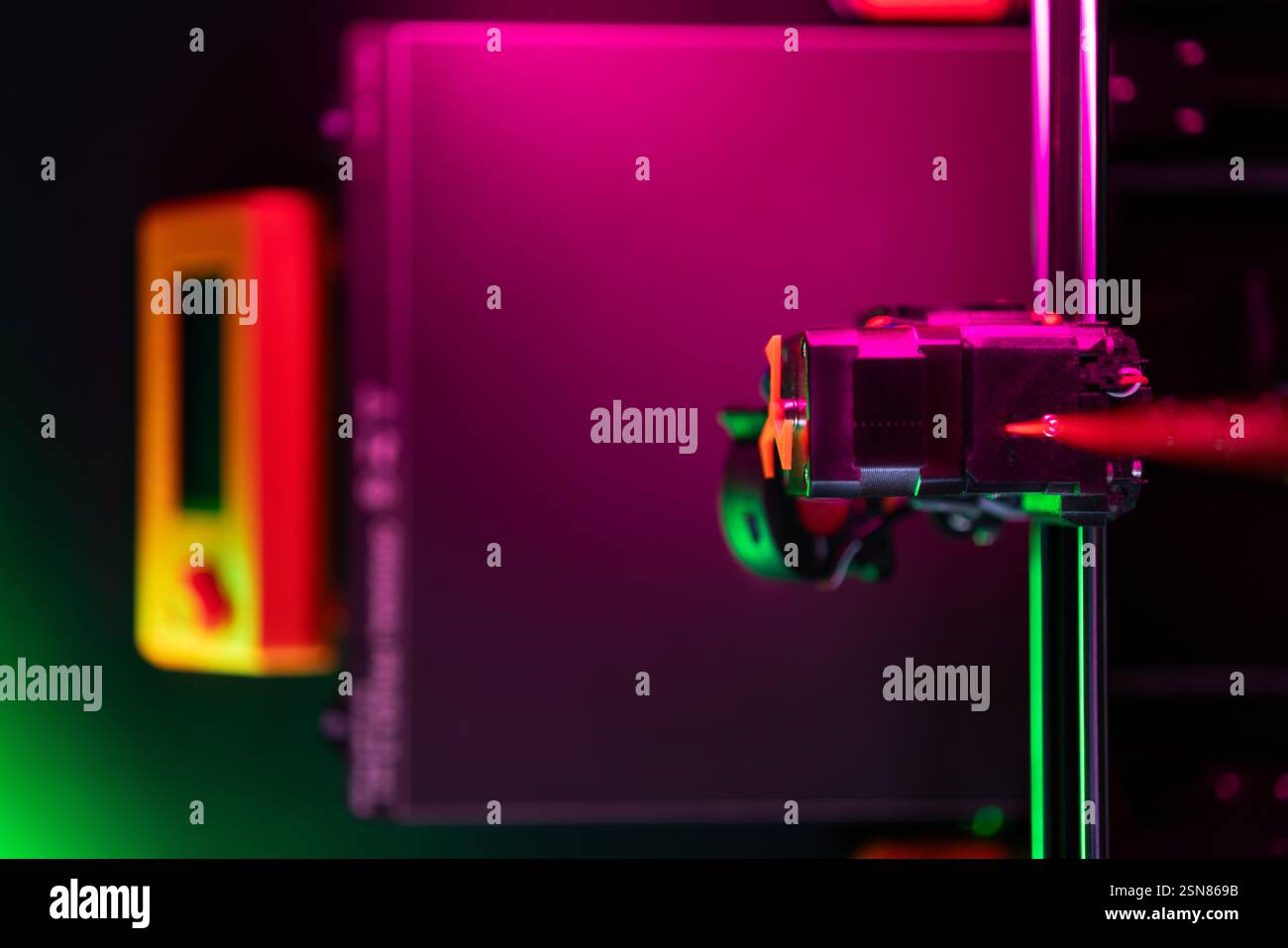 3D-Drucker Hot Table Oberfläche von oben dunkel Neon hellorange Details Rosa und Grün Extruderkopf Führung Stockfoto