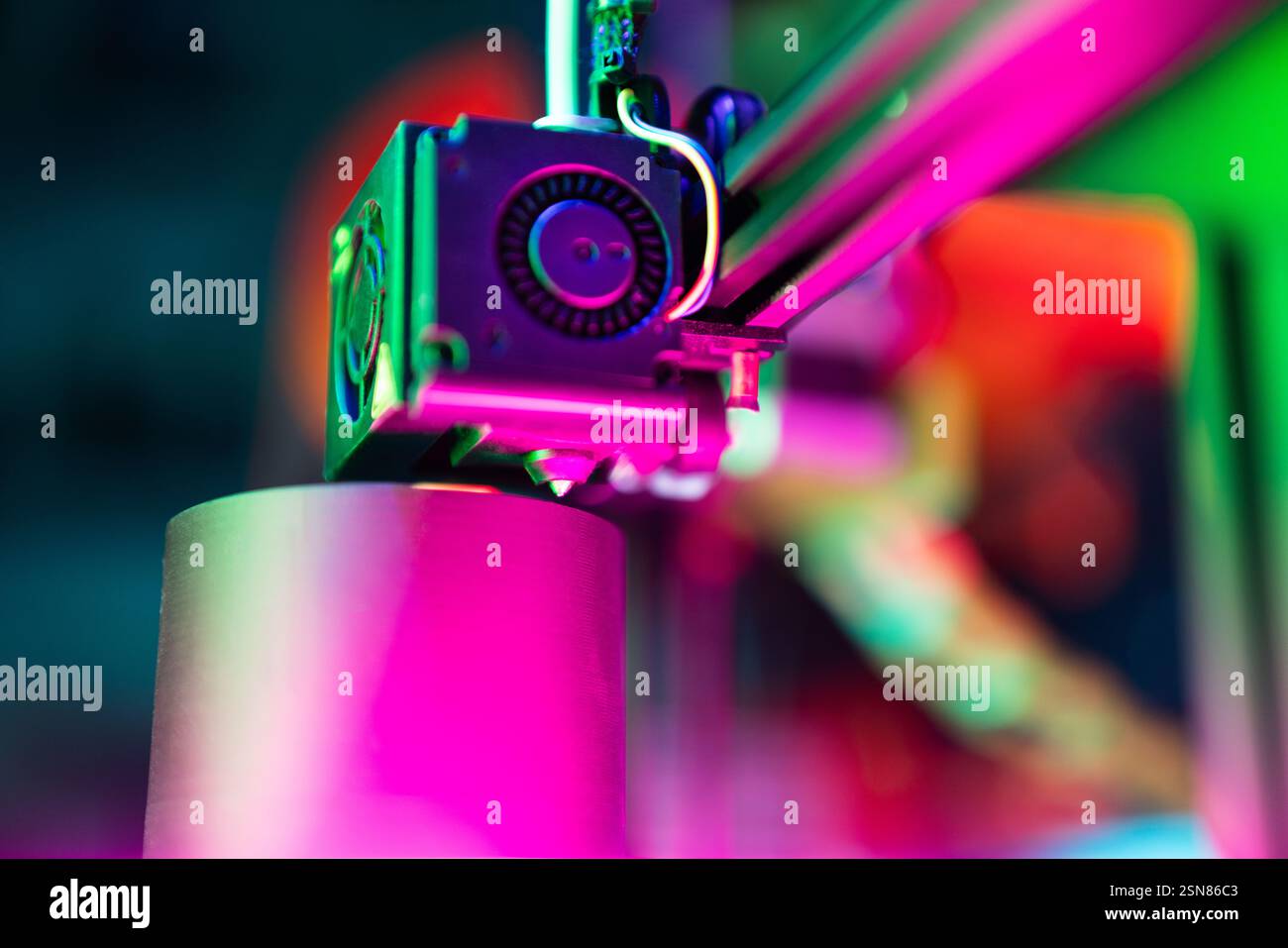 Druckarm-Düse für bedruckte 3D-Objekte lebendiger Nahextruder, der durch Neonlicht hervorgehoben wird und innovative Hobbytechnologie repräsentiert Stockfoto