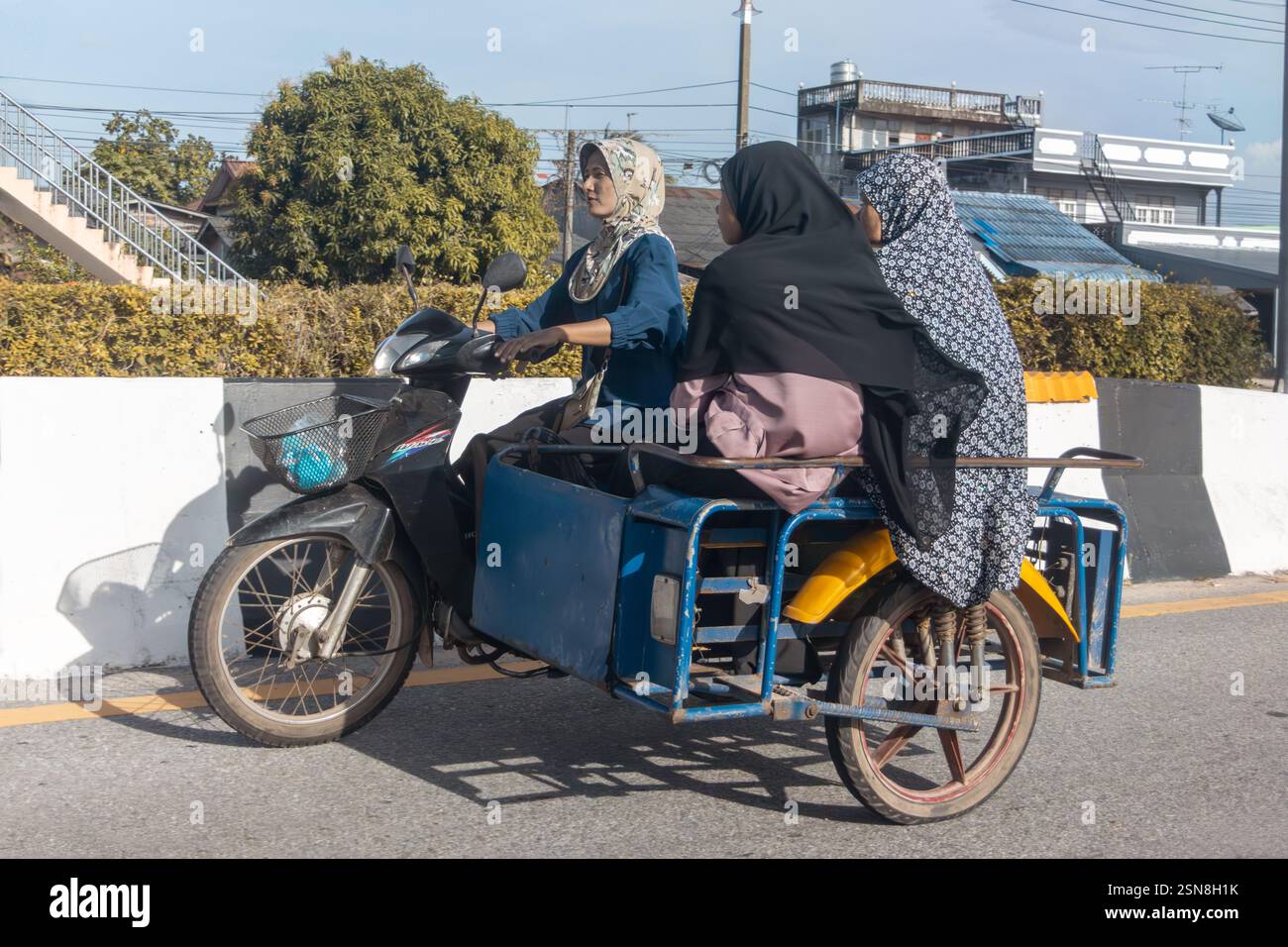 YALA, THAILAND, 02. März 2024, Eine Gruppe von Frauen in muslimischer Kleidung fährt ein Motorrad mit einem Beiwagen Stockfoto