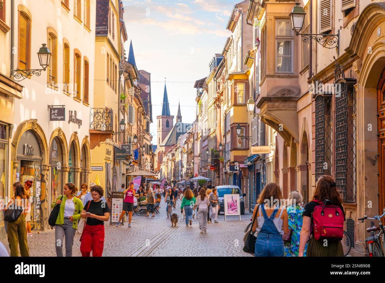 Touristen und einheimische Franzosen genießen die Geschäfte und Cafés in einer Straße aus halbhölzernen Gebäuden im mittelalterlichen Straßburg Frankreich. Stockfoto