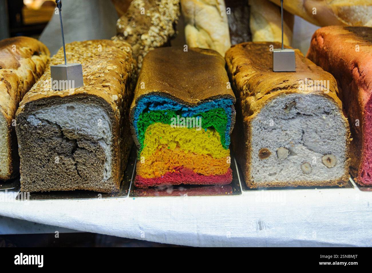 Drei Brote mit frisch gebackenem Brot, darunter einer mit Regenbogenfarben, verkauft zu Ehren der Pride Parade in Madrid, Spanien. Stockfoto