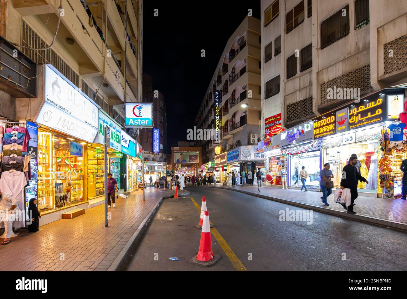 Abendlicher Blick auf ein geschäftiges Viertel des Gold Souk mit beleuchteten Geschäften, die Gewürze, Gold und andere Waren in Dubai, Vereinigte Arabische Emirate, verkaufen. Stockfoto