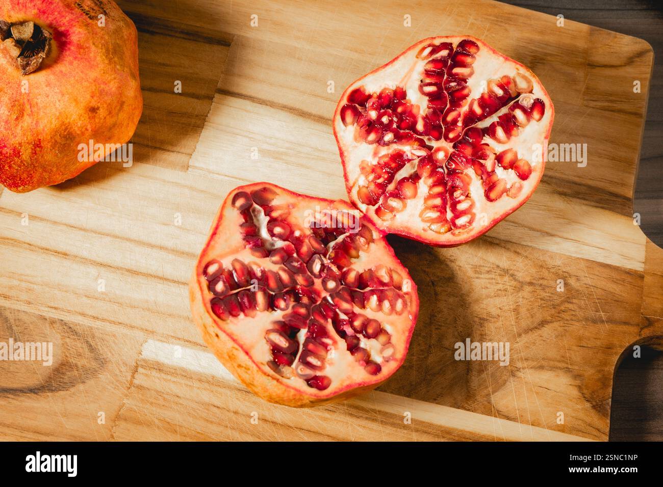 Pomegranaten in zwei Hälften auf hölzernem Hintergrund. Stockfoto