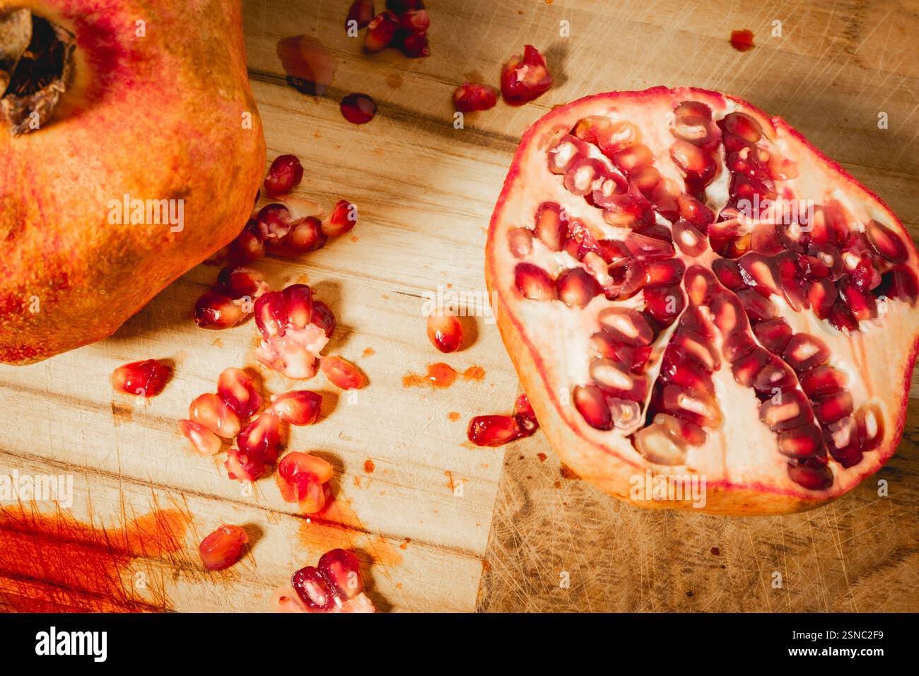 Pomegranaten in zwei Hälften auf hölzernem Hintergrund. Stockfoto