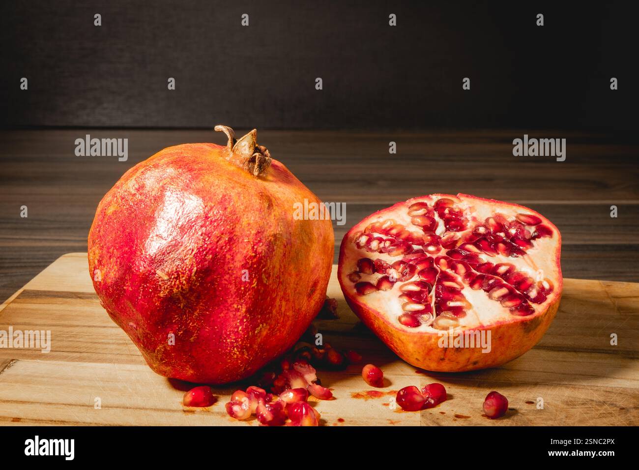 Pomegranaten in zwei Hälften auf hölzernem Hintergrund. Stockfoto