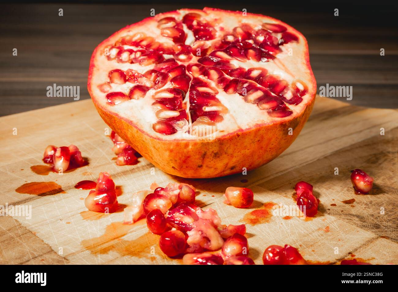 Pomegranaten in zwei Hälften auf hölzernem Hintergrund. Stockfoto