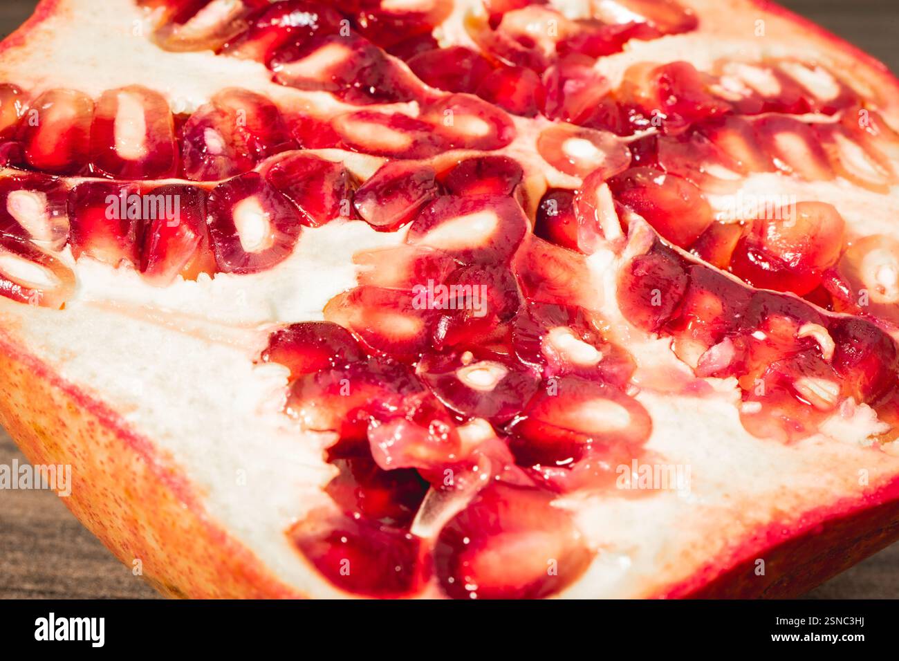 Pomegranaten in zwei Hälften auf hölzernem Hintergrund. Stockfoto