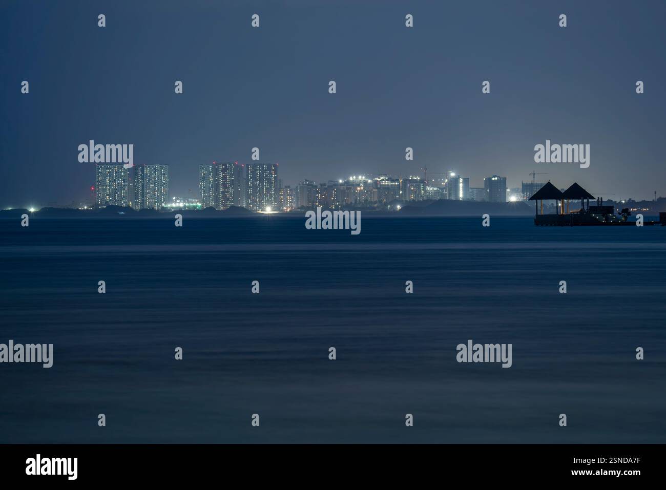Einzigartige Landschaft über die Malediven. Die Hauptstadt Malé liegt im Hintergrund. Beleuchteter kleiner Ruheplatz mit Bett im Vordergrund. Stockfoto