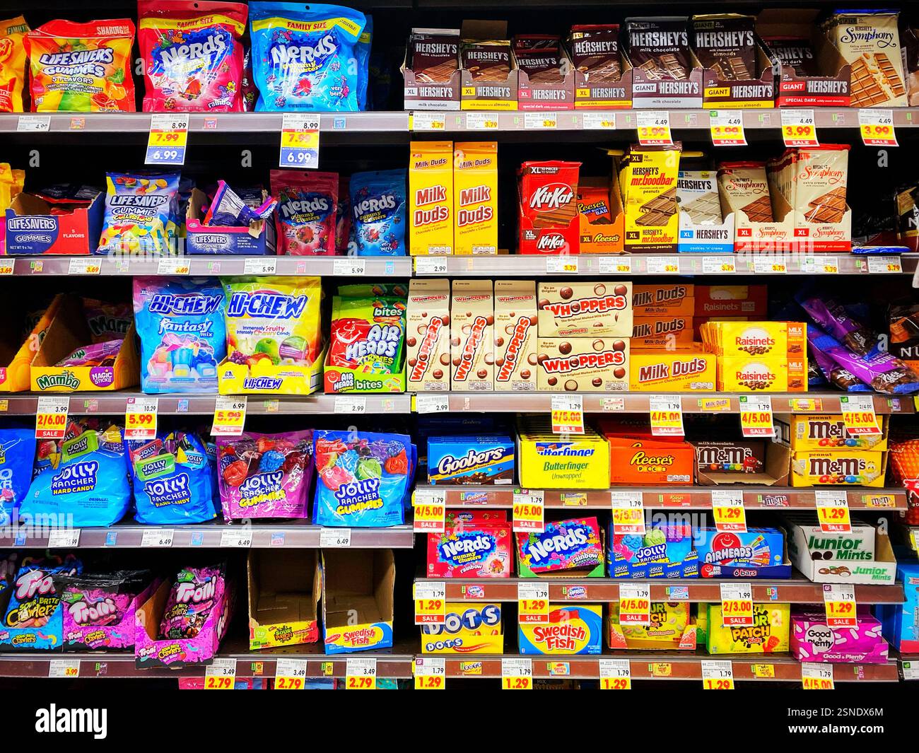 Verschiedene Süßigkeiten und Süßigkeiten zum Verkauf in einem amerikanischen Supermarkt. Whoppers, Kit Kats, Hershey Bars, Nerds, Hi-Chews, Luftköpfe, Jolly Ranchers, Milk Duds, Junior Mints, M&M, Dotss, Schwedischer Fisch, Trolli, Rosinen, Butterfinger, und Reese's Erdnussbutter-Becher in den Regalen des Lebensmittelgeschäfts. Stockfoto