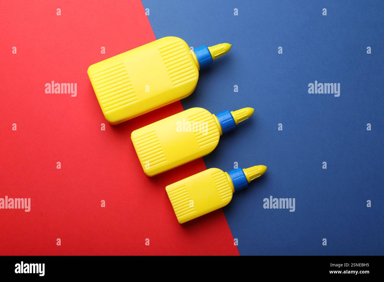 Flaschen Klebstoff auf farbigem Hintergrund, flach Stockfoto