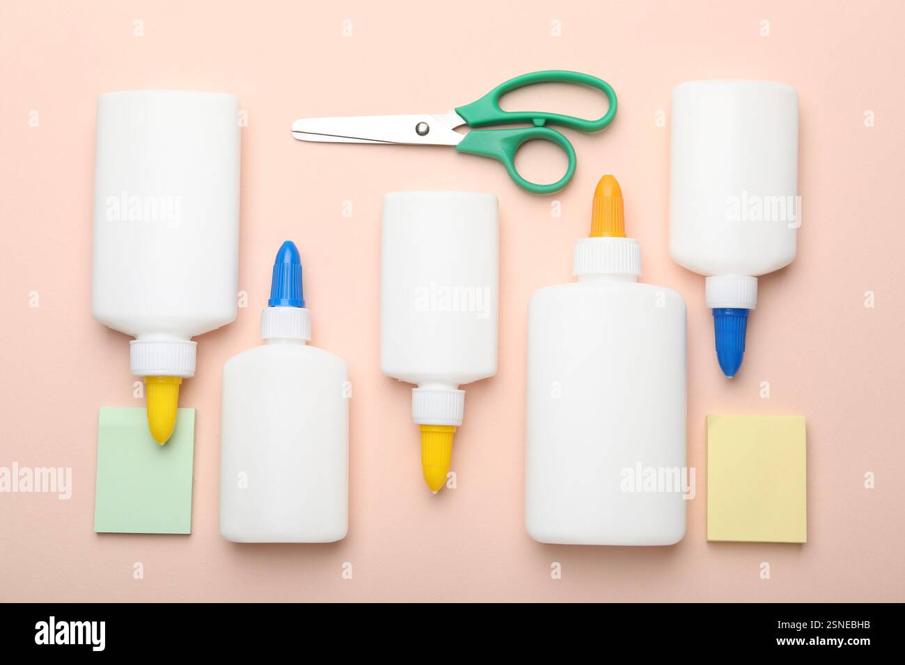 Flaschen mit Leim, Schere und Notizen auf beigem Hintergrund, flach gelegt Stockfoto