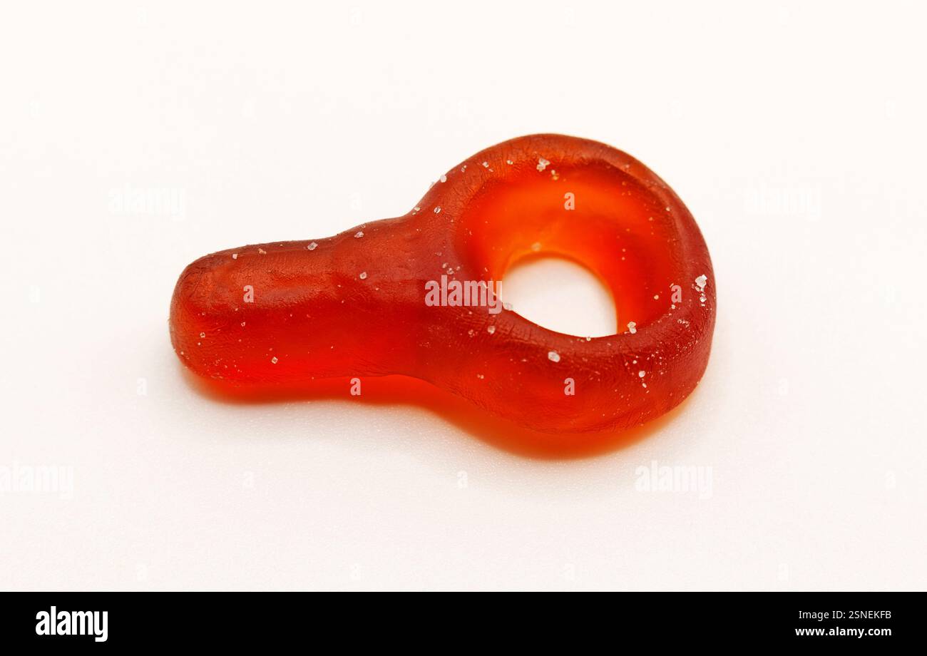 Ein durchscheinendes braunes, gummiartiges Bonbon mit Cola-Geschmack in Form eines Babyschnullers, fotografiert auf weißem Hintergrund. Dieses neue Bonbon kombiniert das beliebte Stockfoto