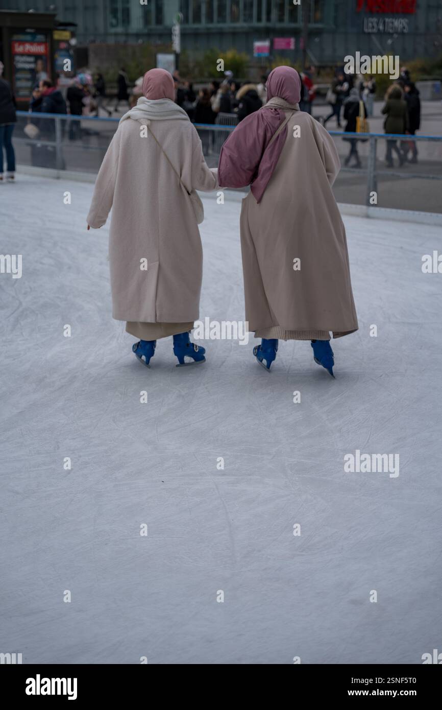 Freunde, die einen Wintertag auf Schlittschuhen in einer belebten Eisbahn verbringen Stockfoto