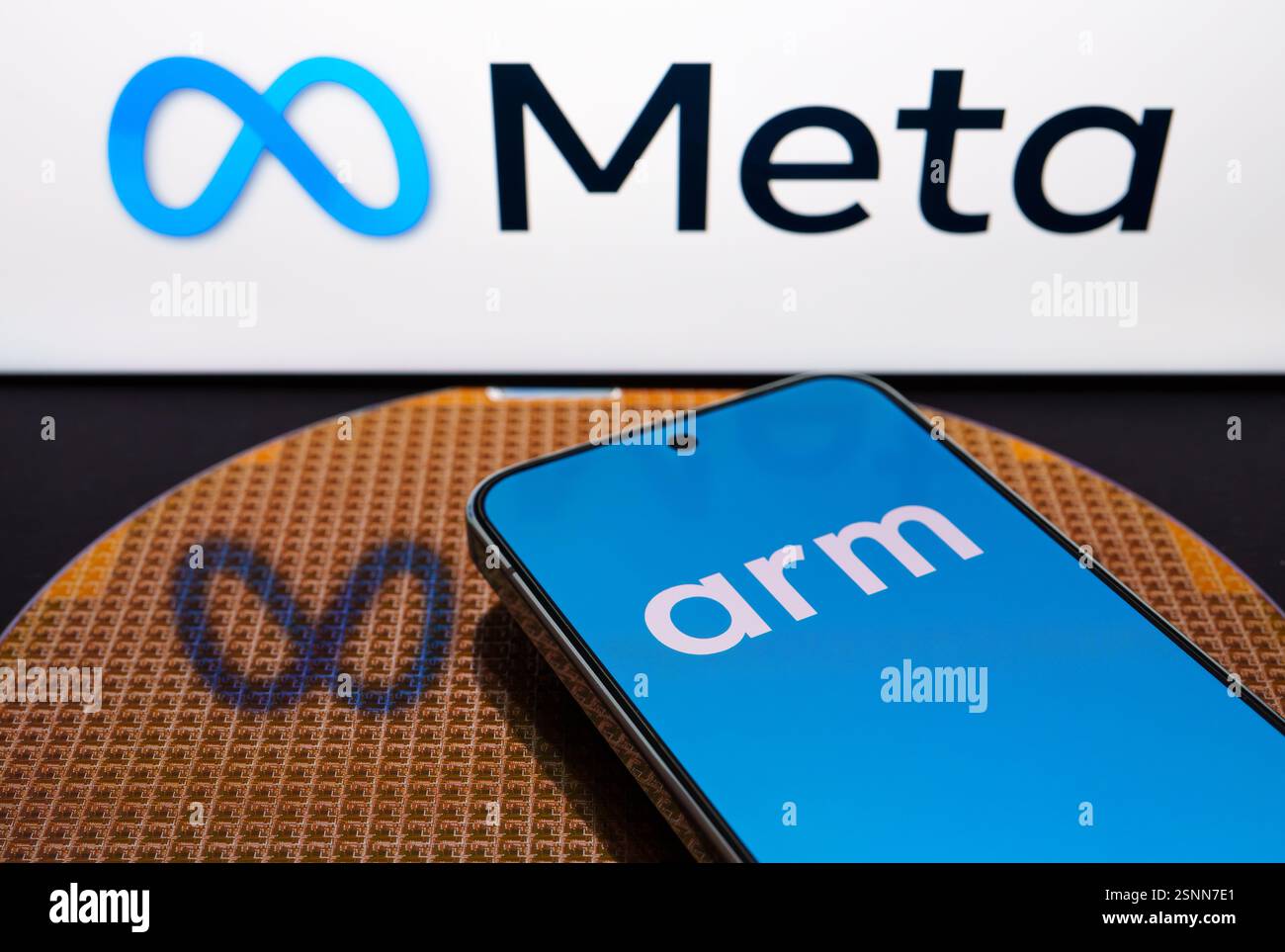 ARM Holdings Logo auf dem Smartphone, das auf einem Halbleiterwafer mit Chips und Meta Platforms Logo auf dem Hintergrund platziert wird. Stafford, Vereinigtes Königreich Stockfoto