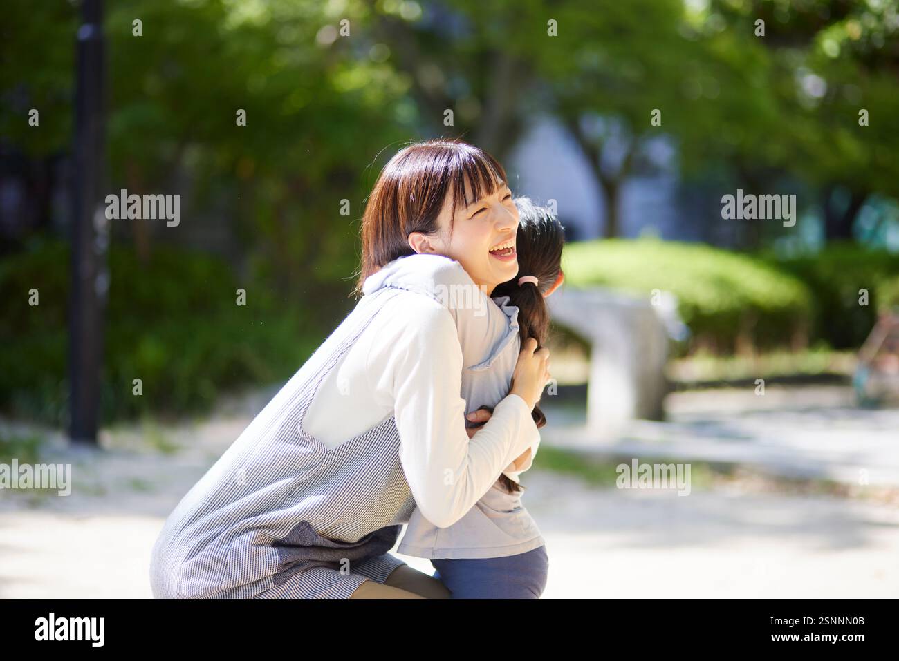 Lächelnde Kinderbetreuerin, die ein Kind umarmt Stockfoto