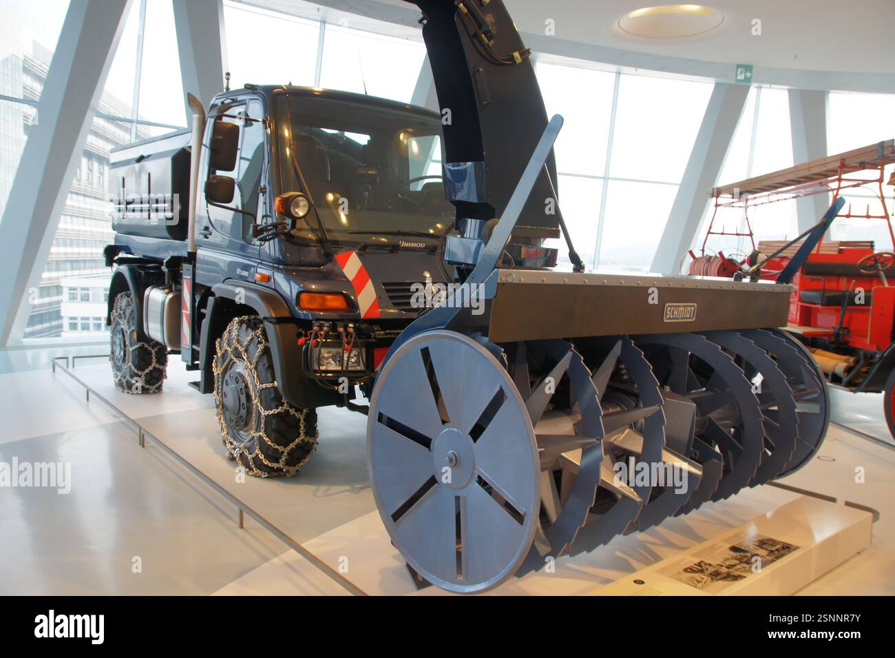 Deutschland, München. Der leistungsstarke Mercedes-Benz Unimog mit Schneepflug-Anbaugerät bewältigt harte Winterbedingungen. Ein Beweis für deutsche Ingenieurskunst Stockfoto