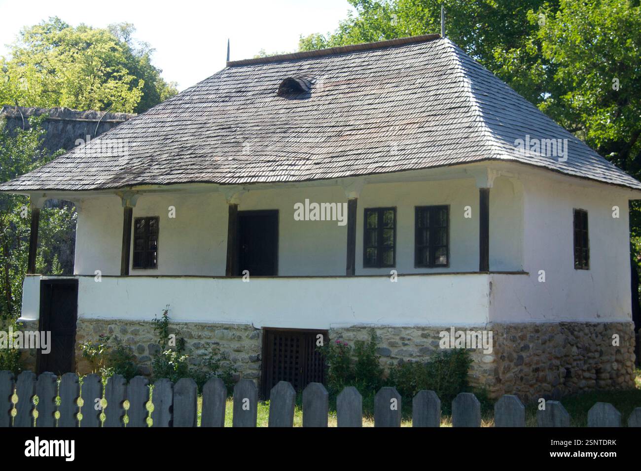 Das Dorfmuseum, Bukarest, Rumänien. Holzhaus aus dem 19. Jahrhundert aus der Grafschaft Arges, mit Holzschindeldach, Balkon, Steinfundament und Keller. Stockfoto
