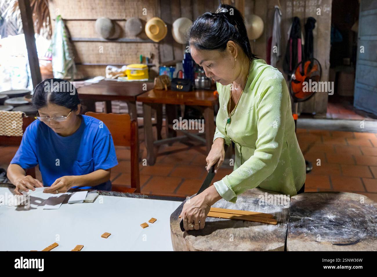 Zwei Personen konzentrieren sich auf die Zubereitung traditioneller Packungen von Kokosnussbonbons in einer lokalen Kokosnussbonbons-Fabrik, Quoi Son, Vietnam. Montag, 11. November 2024 Stockfoto
