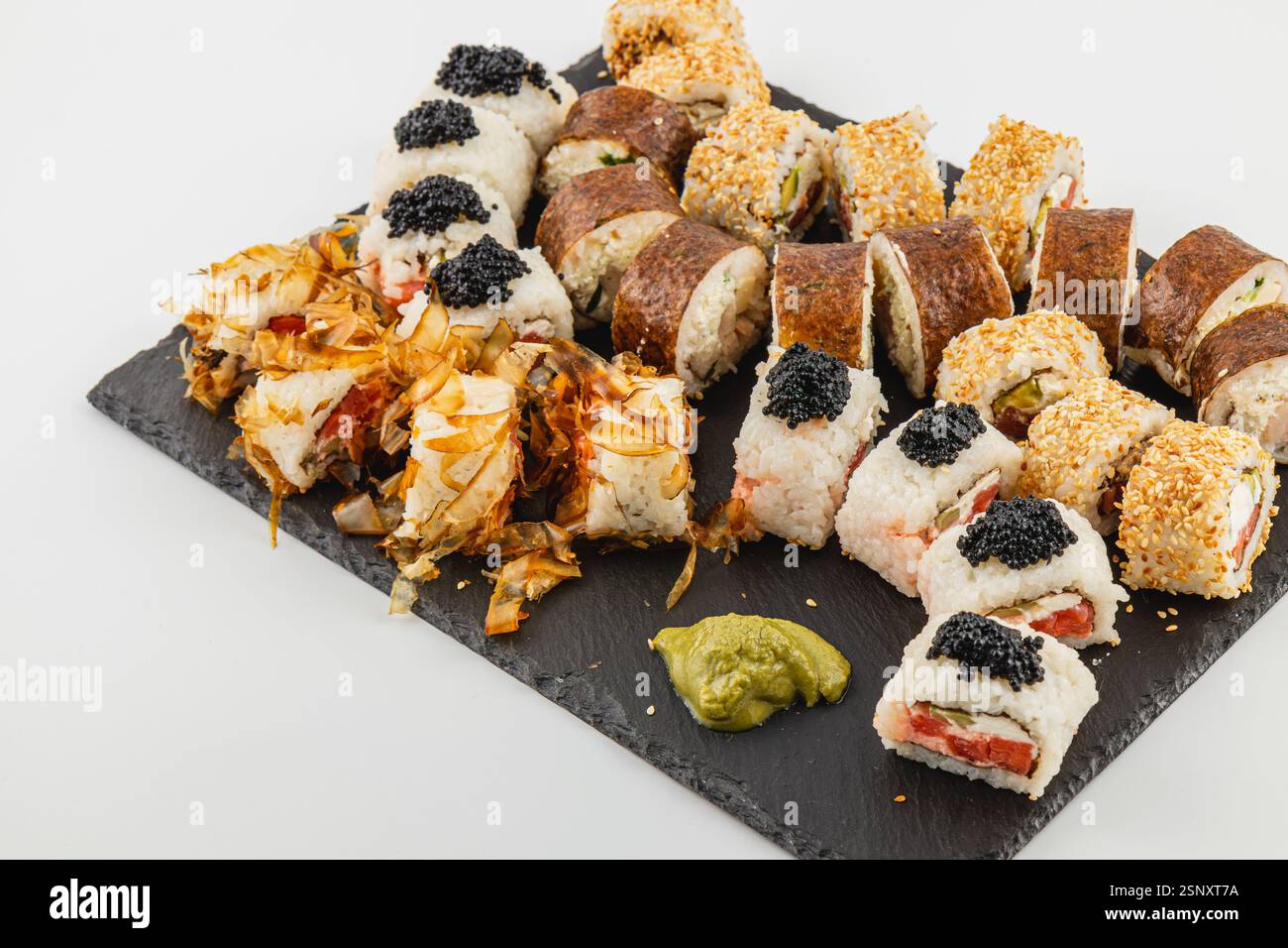 Eine wunderschön angeordnete Sushi-Platte zeigt eine Vielzahl von Brötchen, die farbenfrohe Zutaten und Beläge hervorheben, ideal für ein geselliges Abendessen Stockfoto