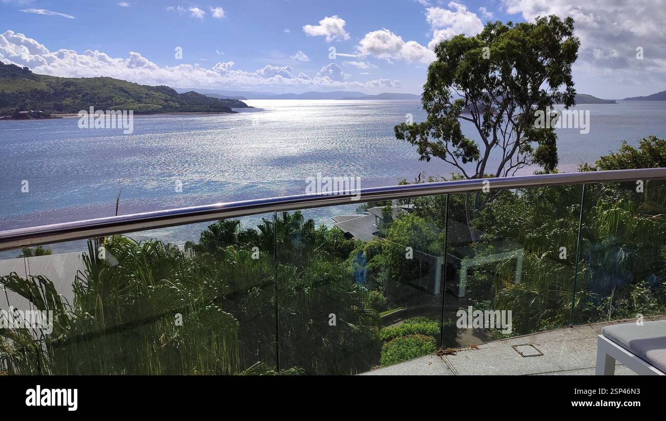 Blick auf den Strand vom Balkon mit Glasgeländern. Ein entspannender Ort, um die Sonne zu genießen und die Meereslandschaft zu genießen. Traumhafter Urlaubsort. Hamilton Island Stockfoto