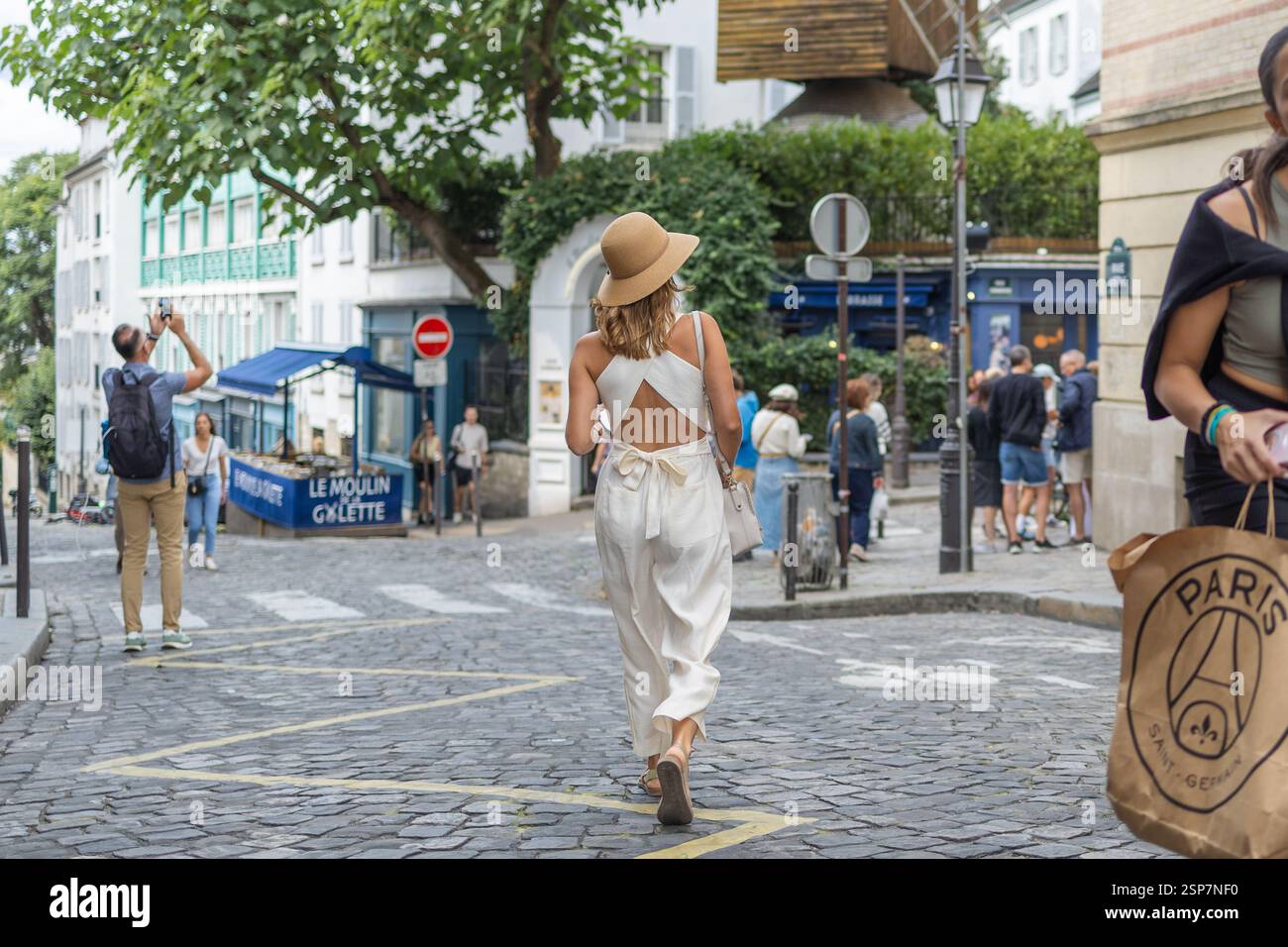 Stilvolle Frau in weißem Outfit, die durch die Straßen von Montmartre in Paris schlendert. Stockfoto