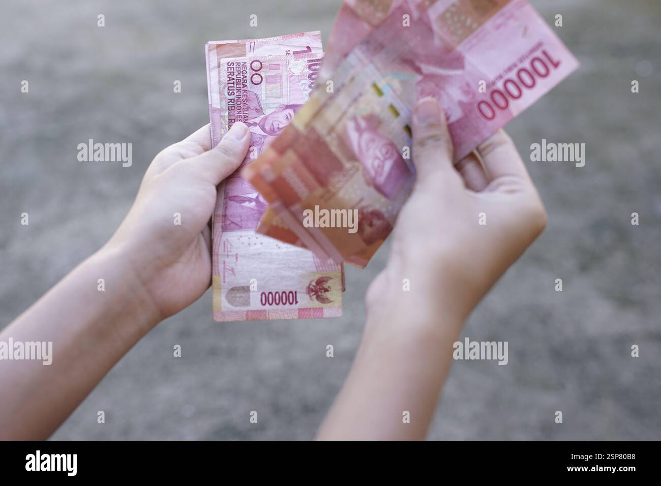 Die Menschen zeigen indonesisches Geld als legales Zahlungsinstrument Stockfoto