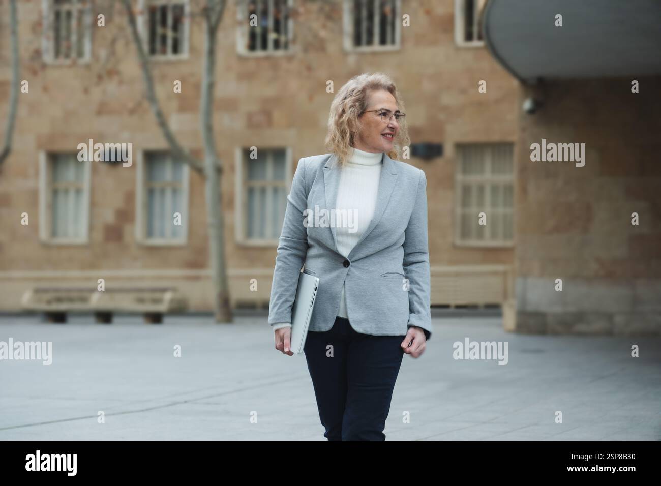 Selbstbewusste Geschäftsfrau, die in urbaner Umgebung spaziert Stockfoto