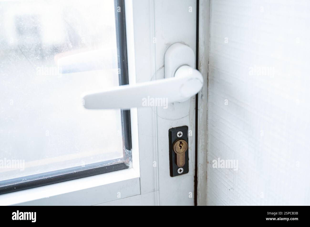 Türgriff aus weißem Kunststoff, Nahaufnahme. Die Tür hat ein Fenster. Eine Nahaufnahme einer Tür Stockfoto