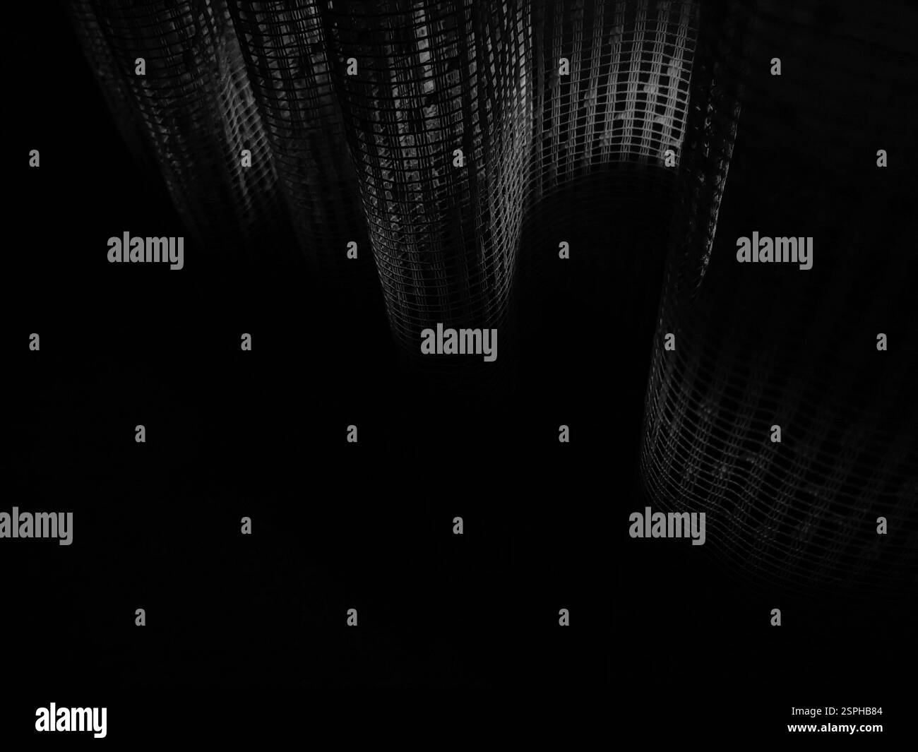 Geschwungene Schatten – sonnendurchflutete Vorhänge in der Dunkelheit Stockfoto