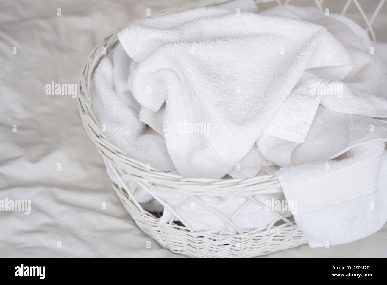Stapel weißer Handtücher in einem Korb auf dem Bett Stockfoto