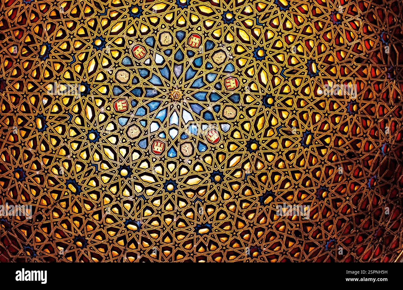 Eine detaillierte Ansicht eines komplexen geometrischen Musters an der Decke mit kunstvollen Mustern in Gold- und Blautönen, die einen faszinierenden visuellen Effekt erzeugen. Stockfoto