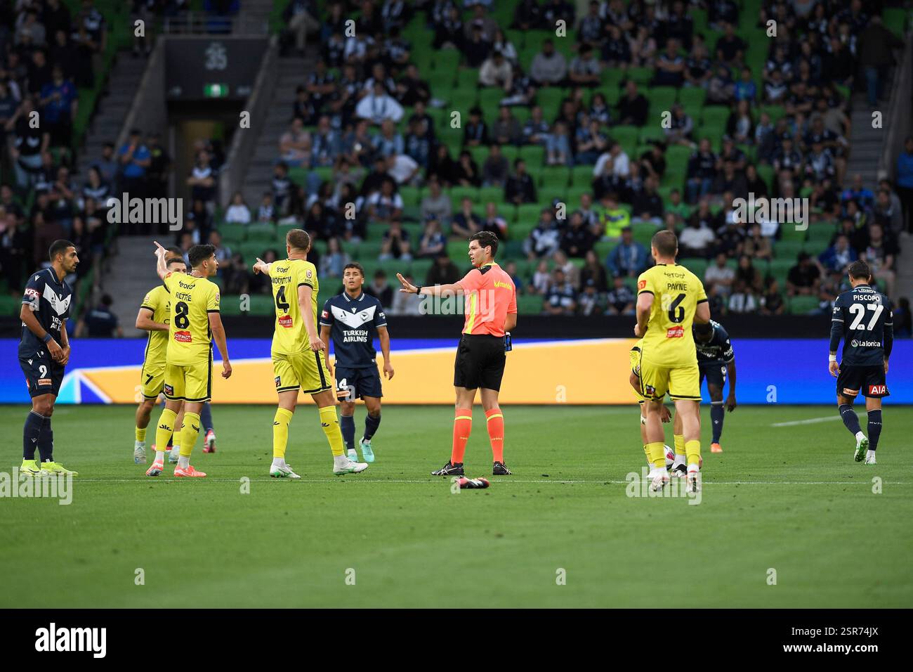 MELBOURNE, AUSTRALIEN. Februar 2025. Im Bild: Match-Schiedsrichter Adam Bavcar gibt dem Verteidiger von Wellington Phoenix Scott Wootton eine Geste, um sich zu beruhigen, nachdem Wellingtons Tim Payne während des 19. Spiels der ISUZU A League, Melbourne Victory gegen Wellington Phoenix, am 14. Februar 2025 im AAMI Park, Melbourne, Australien, einen Schuh verloren hat. Quelle: Karl Phillipson / Alamy Live News Stockfoto