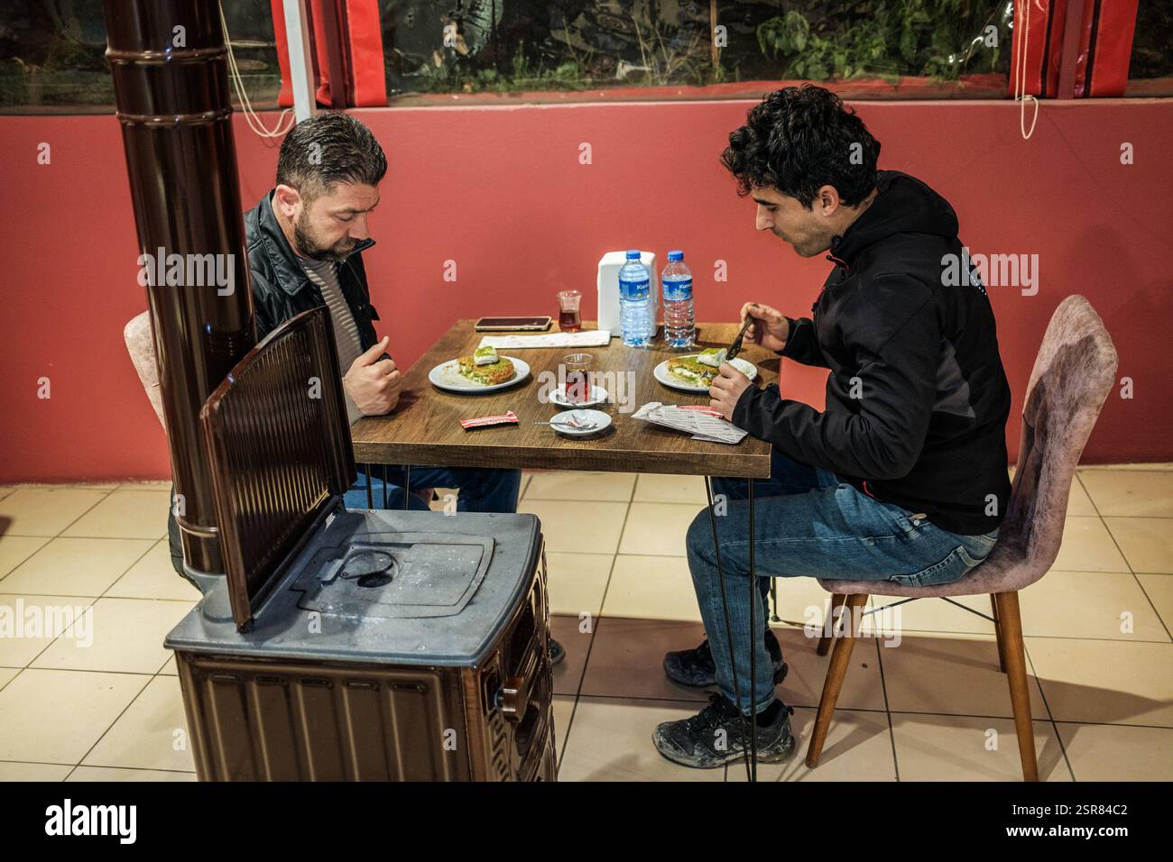 Leute essen Kunafa an einem Tisch. Kunafa, das berühmte Dessert des Nahen Ostens, ist der unentbehrlichste und klarste Geschmack der arabischen Küche. Das Zentrum von Kunafa ist Antakya, eine ehemalige syrische Provinz. Von der osmanischen Zeit bis heute hat Antakya Kunafa seinen Ruf berühmt gemacht. Antakya Kunafa ist eines der wenigen in der Türkei hergestellten Desserts mit Käse. In der Herstellung von Kadayif werden frischer Kunafa-Käse, Butter und Sherbet verwendet. Er wird durch das Kochen von Kunafa-Käse zwischen zwei Lagen Drahtsammelkadayif in einem flachen Tablett und Zugabe von Sherbet zu den gewünschten Süßigkeiten gewonnen Stockfoto
