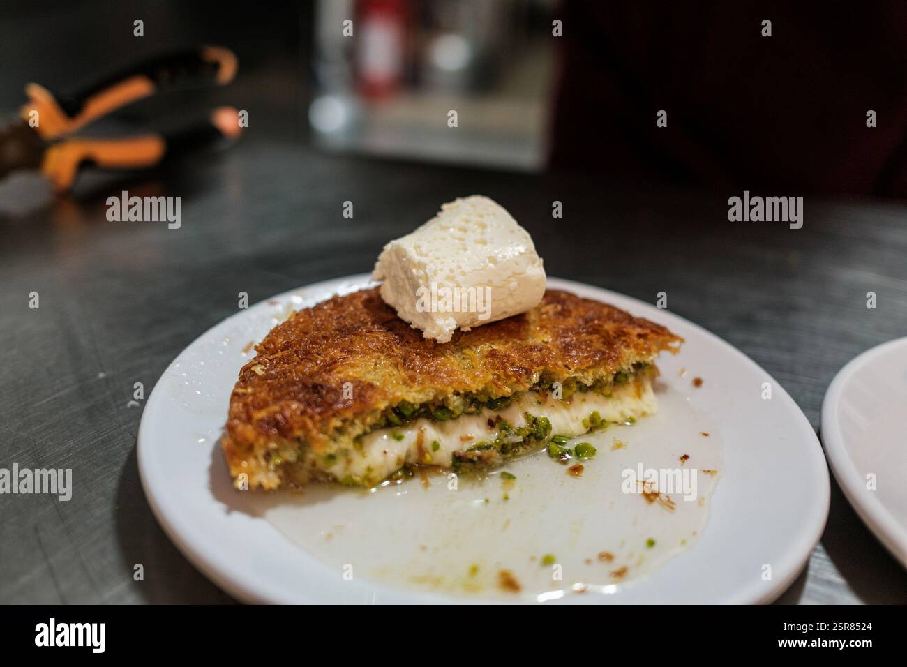 Hatay, Antakya, Türkei. Februar 2025. Bereit zum Servieren von Kunafa. Kunafa, das berühmte Dessert des Nahen Ostens, ist der unentbehrlichste und klarste Geschmack der arabischen Küche. Das Zentrum von Kunafa ist Antakya, eine ehemalige syrische Provinz. Von der osmanischen Zeit bis heute hat Antakya Kunafa seinen Ruf berühmt gemacht. Antakya Kunafa ist eines der wenigen in der Türkei hergestellten Desserts mit Käse. In der Herstellung von Kadayif werden frischer Kunafa-Käse, Butter und Sherbet verwendet. Er wird durch Kochen von Kunafa-Käse zwischen zwei Lagen Drahtsadayif in einem flachen Tablett und Addin gewonnen Stockfoto