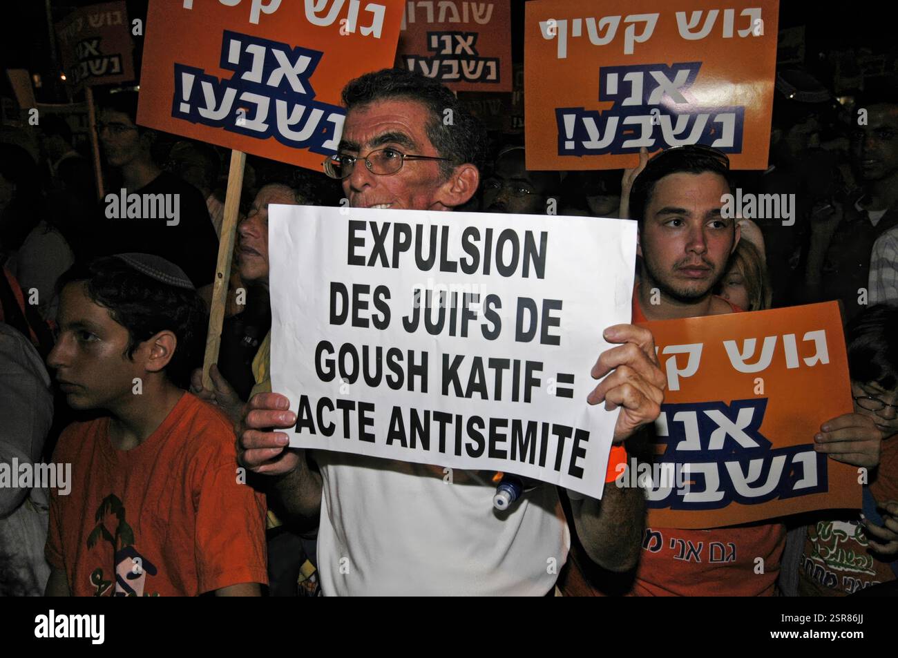 Ein rechtsextremer Anhänger hält ein Schild auf Französisch mit der Aufschrift "Vertreibung der Juden in Gusch Kattif ist ein Akt des Antisemitismus" während einer Demonstration gegen den israelischen Militärzug aus dem Gazastreifen am 11. August 2005 in Tel Aviv Israel. Mehr als 200000 versammelten sich auf dem Rabin-Platz in Tel Aviv, um gegen die Evakuierung des Gazastreifens und des nördlichen Westjordanlands zu protestieren. Viele orangene Bänder um ihre Köpfe gebunden, eine Farbe, die den Kampfwiderstand symbolisiert. Stockfoto