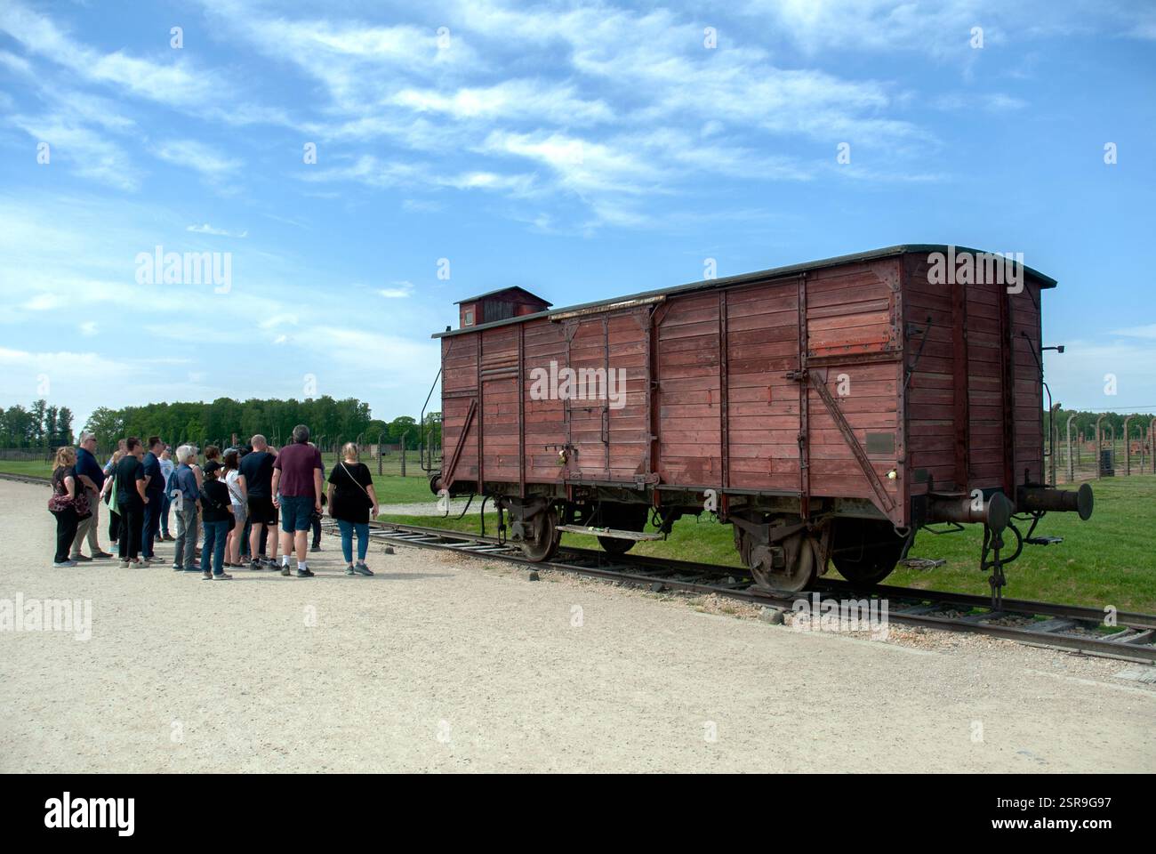 Informative Tour für eine kleine Gruppe von Besuchern des Todeslagers Birkenau - Besucher stehen neben dem Zug Stockfoto