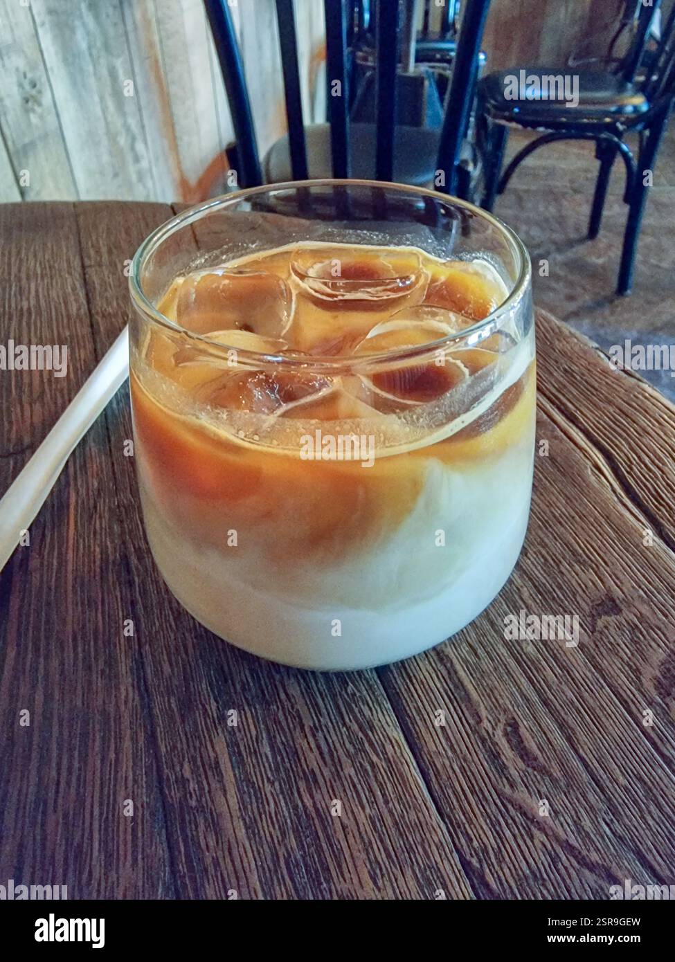 Eiskaffee/Eiskaffee mit Eiswürfeln in einem Glas auf einem Tisch in einem Café Stockfoto