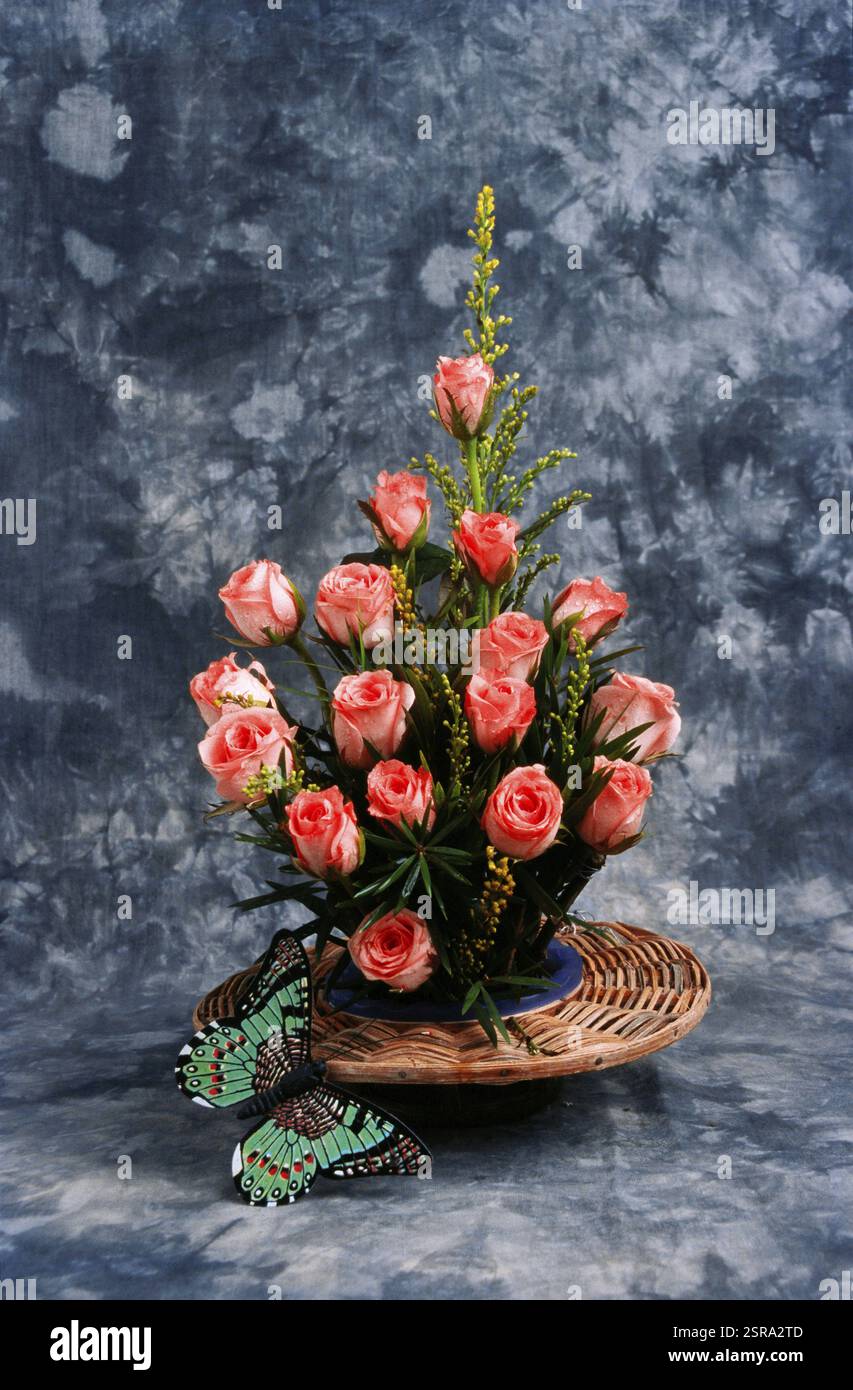 Rosen-Arrangement im Blumenstrauß mit Schmetterling auf grauem Hintergrund Stockfoto