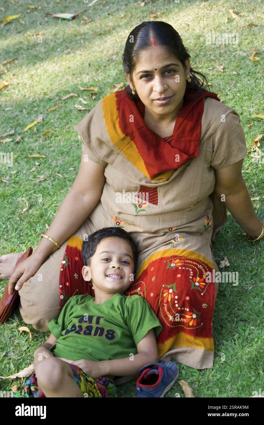 Mutter und Kind sitzen im grünen Grasgarten, Indien MR#707D Stockfoto