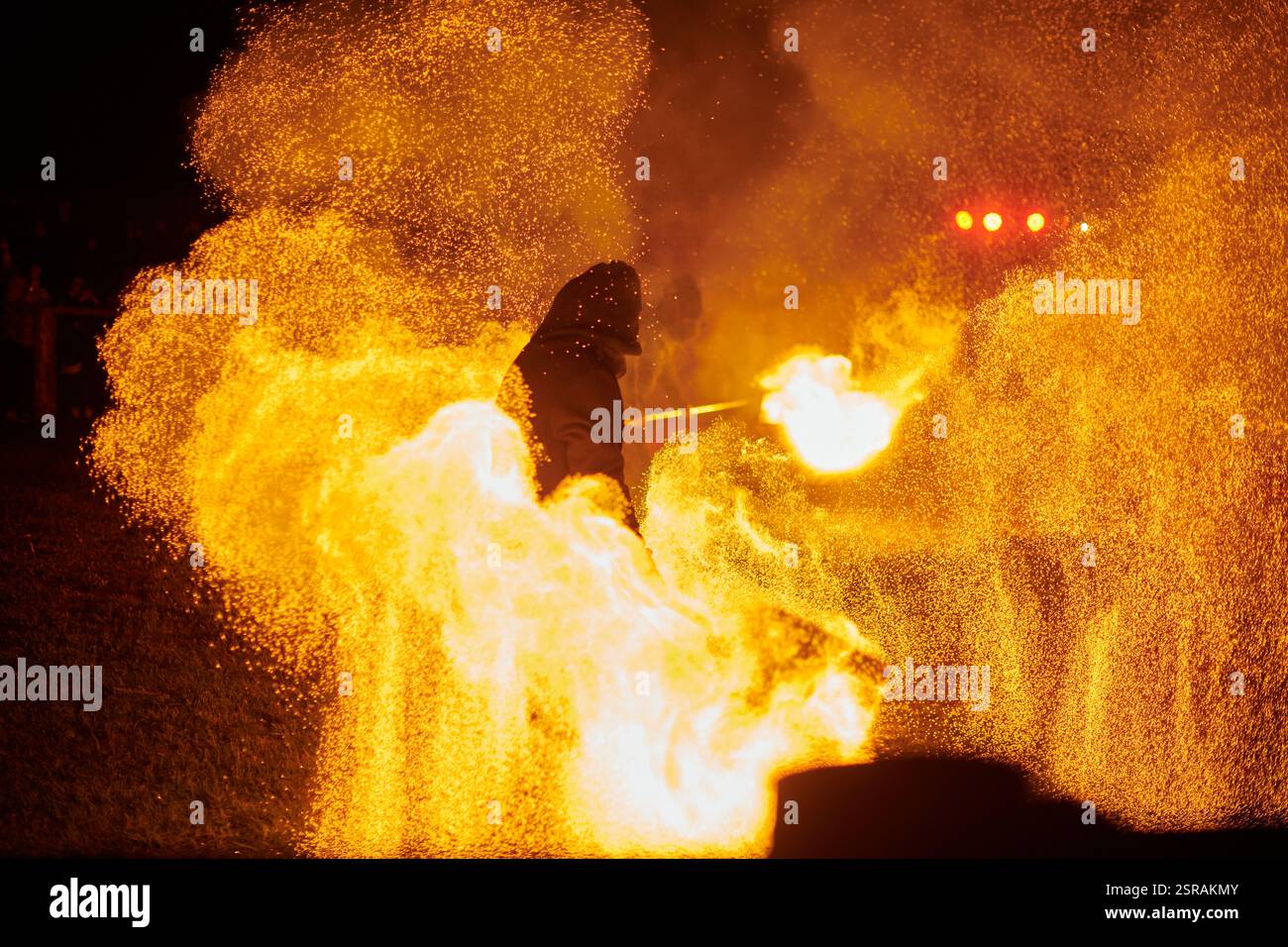 Silhouette zweier Feuerkünstler mit funkelndem Feuerwehrpersonal, das am Nachthimmel ausbricht und die Energie und Kunst der Feuermanipulation während eines Outdours zeigt Stockfoto