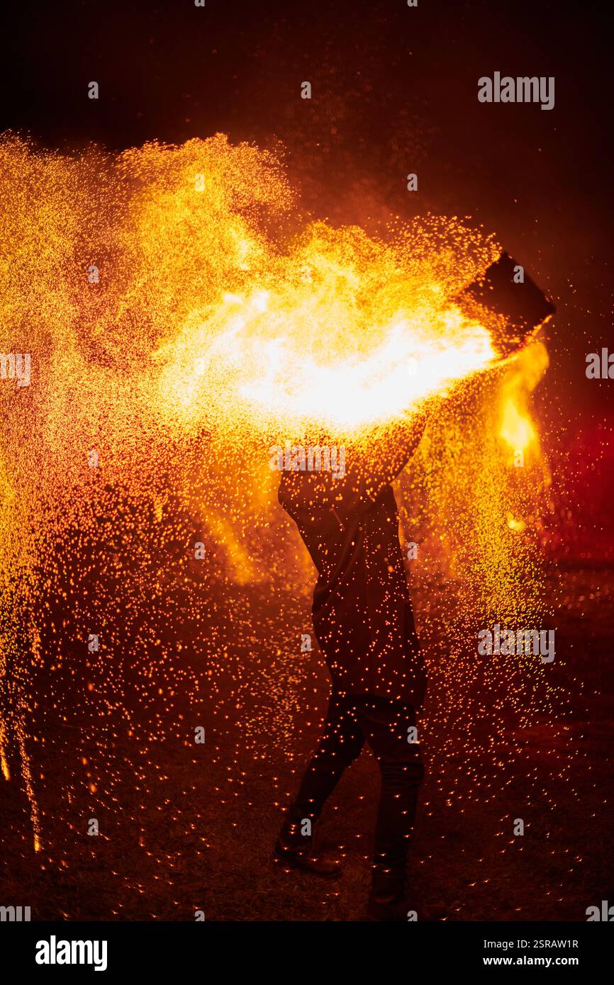 Silhouette zweier Feuerkünstler mit funkelndem Feuerwehrpersonal, das am Nachthimmel ausbricht und die Energie und Kunst der Feuermanipulation während eines Outdours zeigt Stockfoto