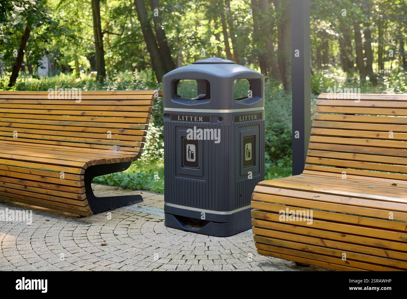 Holzbänke und moderner Abfallbehälter in ruhiger Parkumgebung bieten Komfort und Sauberkeit, umgeben von lebendigem Grün, perfekt zum Entspannen Stockfoto