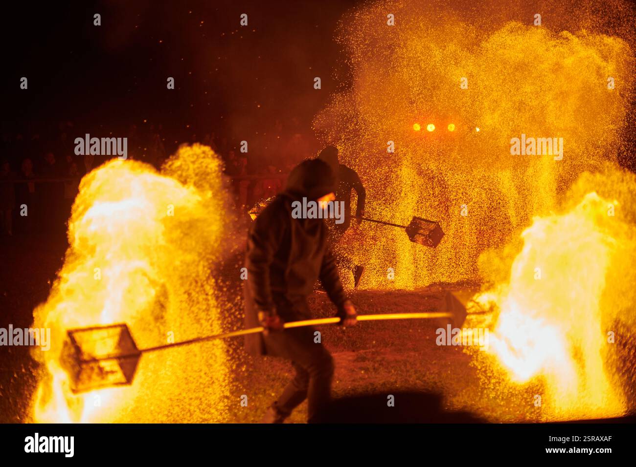 Silhouette zweier Feuerkünstler mit funkelndem Feuerwehrpersonal, das am Nachthimmel ausbricht und die Energie und Kunst der Feuermanipulation während eines Outdours zeigt Stockfoto