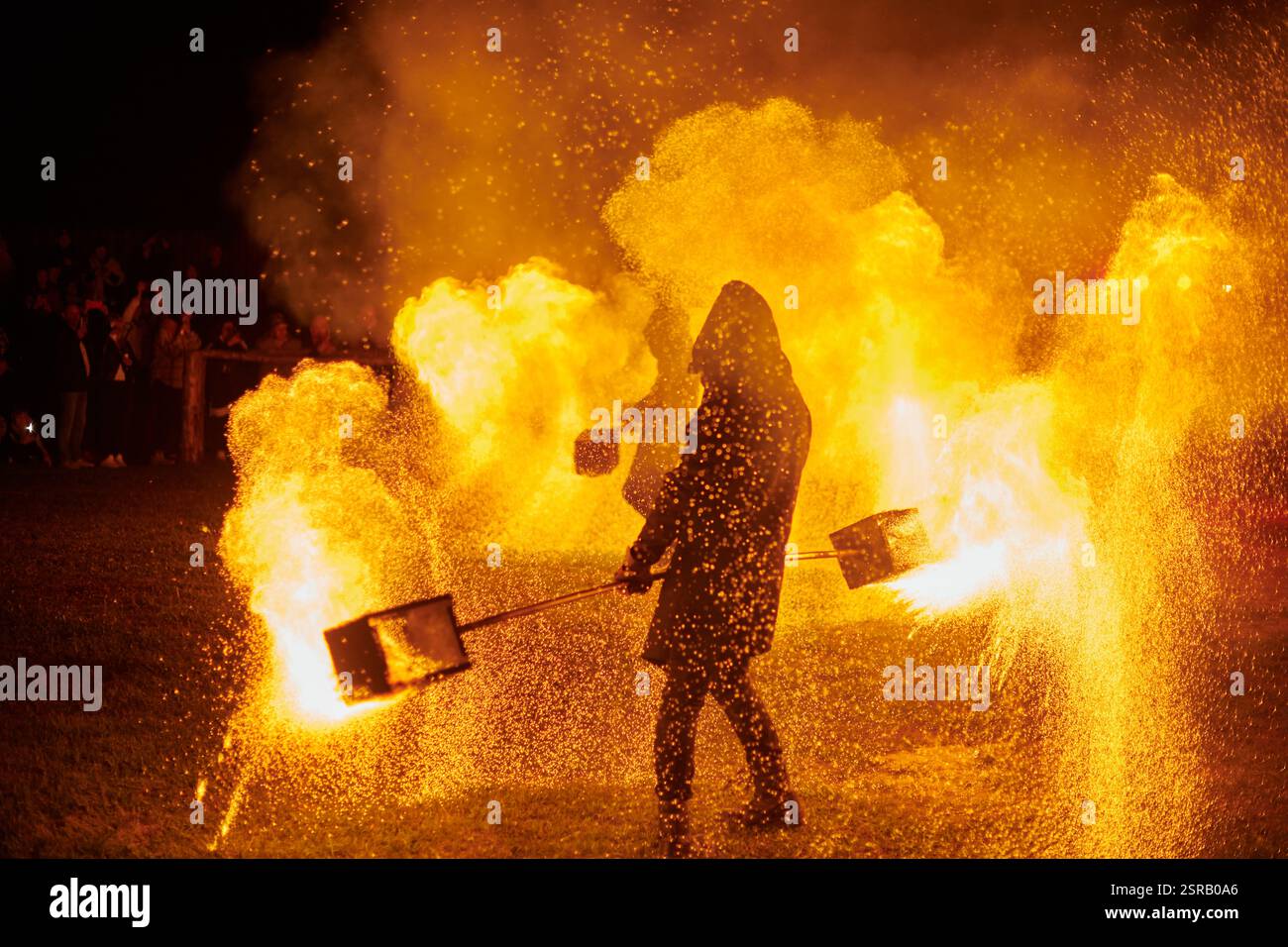 Silhouette zweier Feuerkünstler mit funkelndem Feuerwehrpersonal, das am Nachthimmel ausbricht und die Energie und Kunst der Feuermanipulation während eines Outdours zeigt Stockfoto