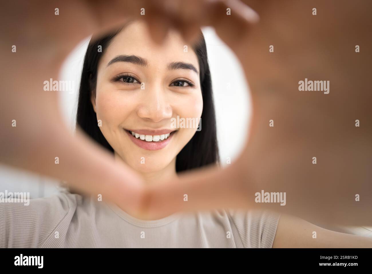 Nahaufnahme des Gesichts einer Frau, die die Kamera mit den Händen umrahmt Stockfoto