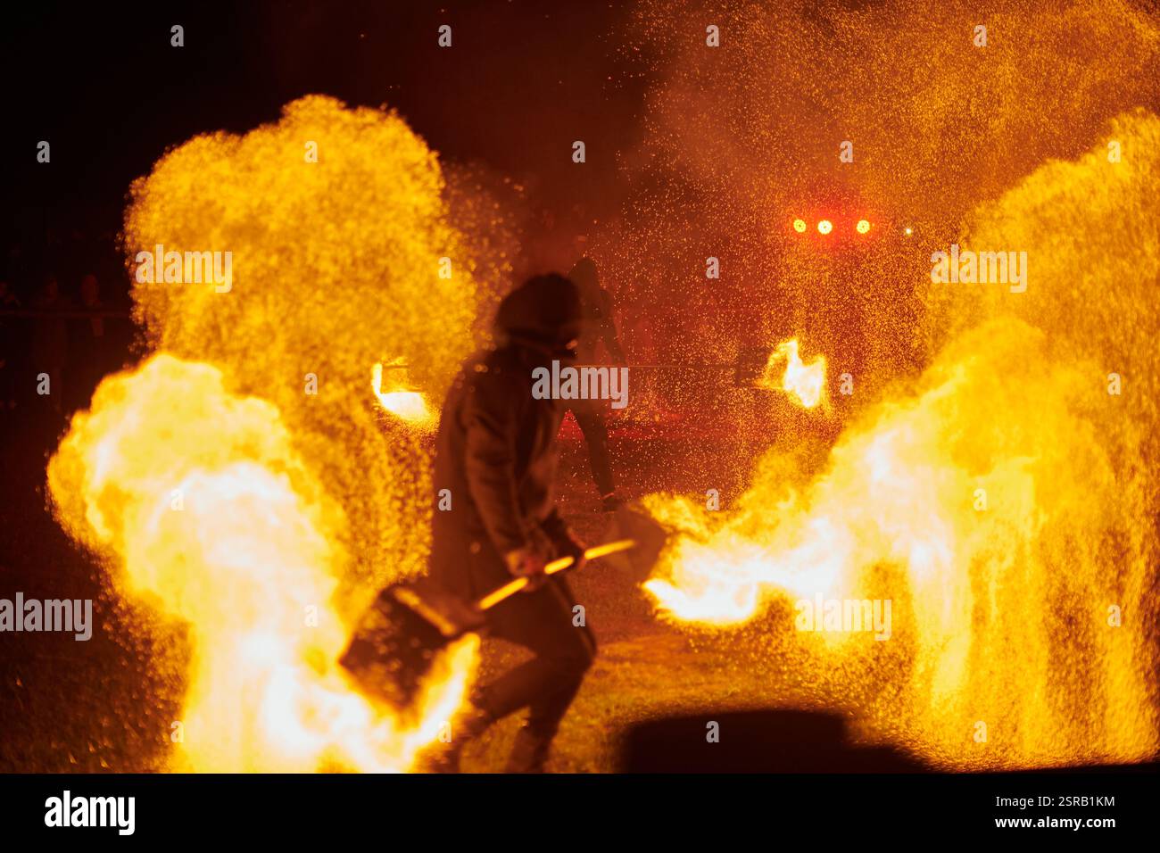 Silhouette zweier Feuerkünstler mit funkelndem Feuerwehrpersonal, das am Nachthimmel ausbricht und die Energie und Kunst der Feuermanipulation während eines Outdours zeigt Stockfoto