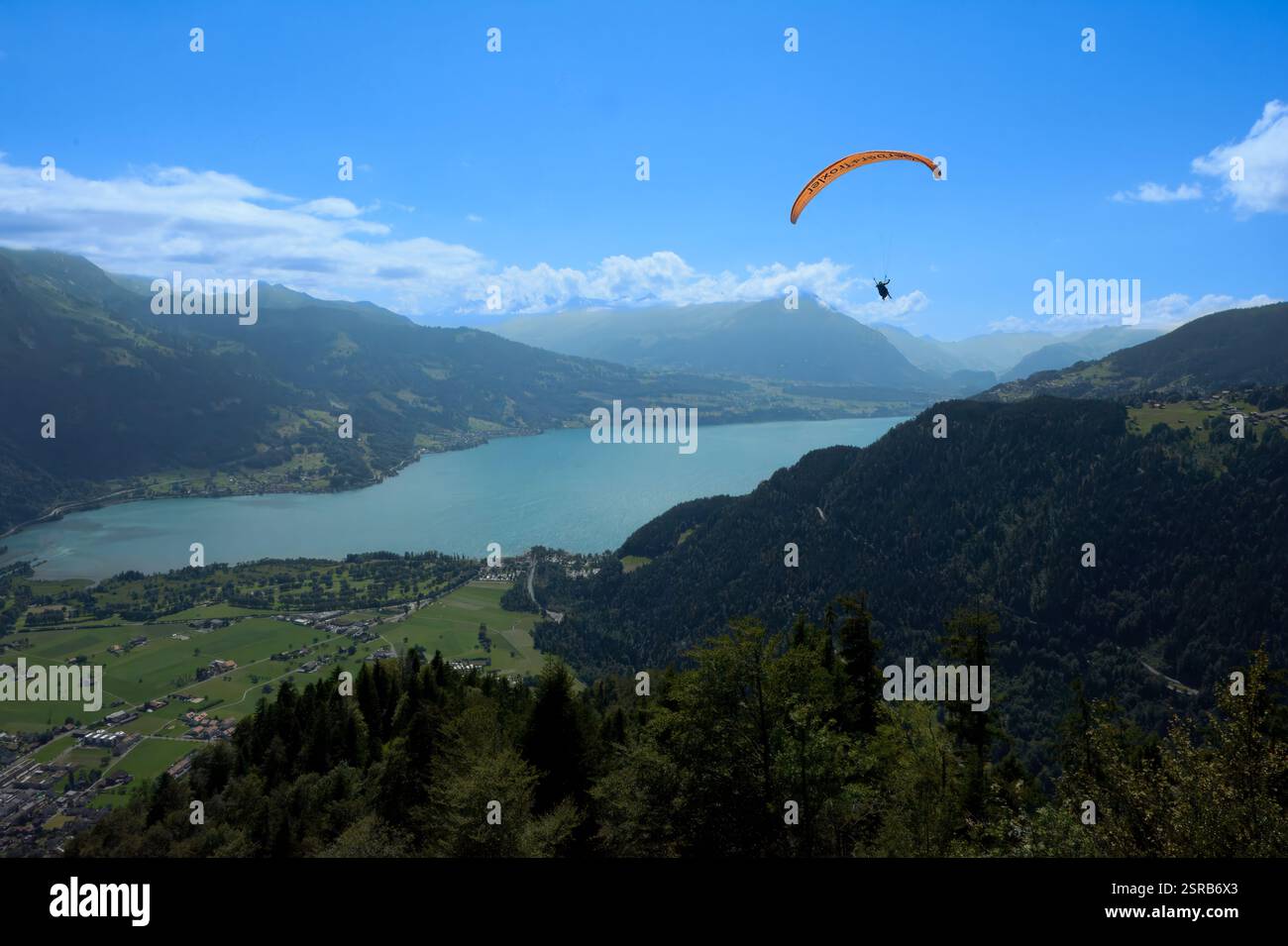 Ein Gleitschirmflieger schwingt hoch über einem atemberaubenden Bergsee und bietet atemberaubende Ausblicke. Das Bild fängt den Nervenkitzel von Abenteuersportarten und landschaftlich reizvollen Landschaften ein. Stockfoto Ein Gleitschirmflieger schwingt hoch über einem atemberaubenden Bergsee und bietet atemberaubende Ausblicke. Das Bild fängt den Nervenkitzel von Abenteuersportarten und landschaftlich reizvollen Landschaften ein. Stockfoto