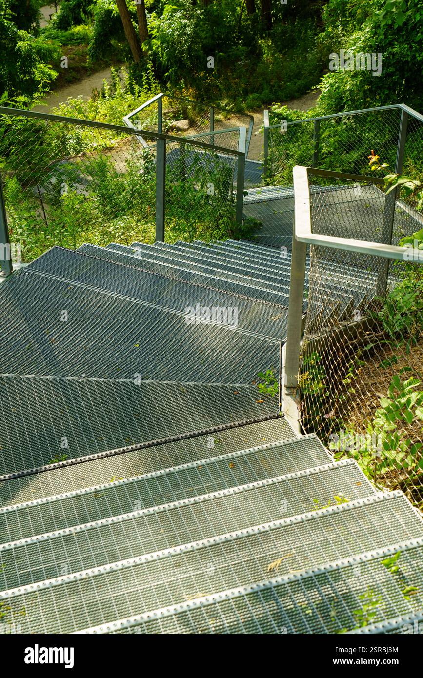 Moderne Fußgängerbrücke aus Aluminium im ökologischen, selbsttragenden Park in Warschau. Park Akcji Burza. Stockfoto