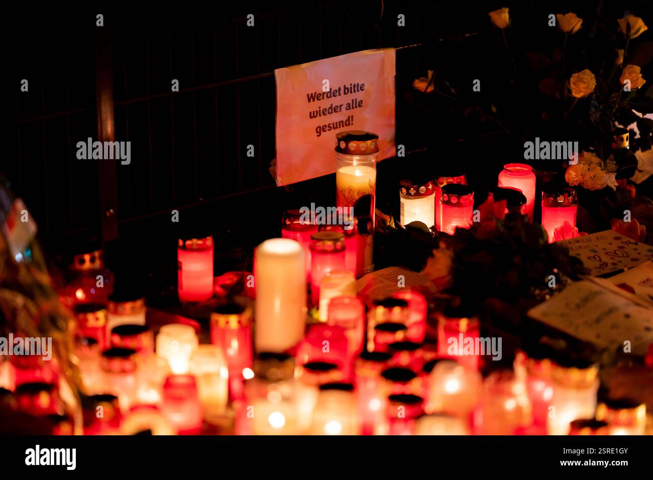 München, Deutschland. Februar 2025. Schild mit der Aufschrift werde bitte wieder alle gesund! - Bitte geht es allen wieder gut! Anlässlich der Gedenkfeier mit Blumen und Kerzen am Ort eines mutmaßlichen Terroranschlags in der bayerischen Hauptstadt München am 13. Februar. Ein 24-jähriger Afghane hat mehrere Personen verletzt, die an einem VERDI-Protest mit einem Auto teilnahmen, eine 37-jährige Frau und ein 2-jähriges Kind sind zwei Tage später ihren Verletzungen erliegen. Quelle: Andreas Stroh/Alamy Live News Stockfoto