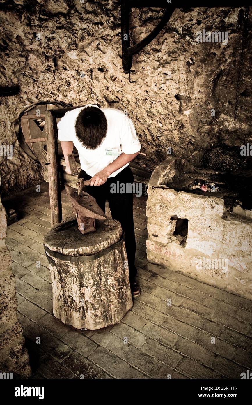 Ein Schmied, der traditionelle Metallbearbeitungstechniken im Krka-Nationalpark in Kroatien in einer historischen Werkstatt demonstriert. Stockfoto